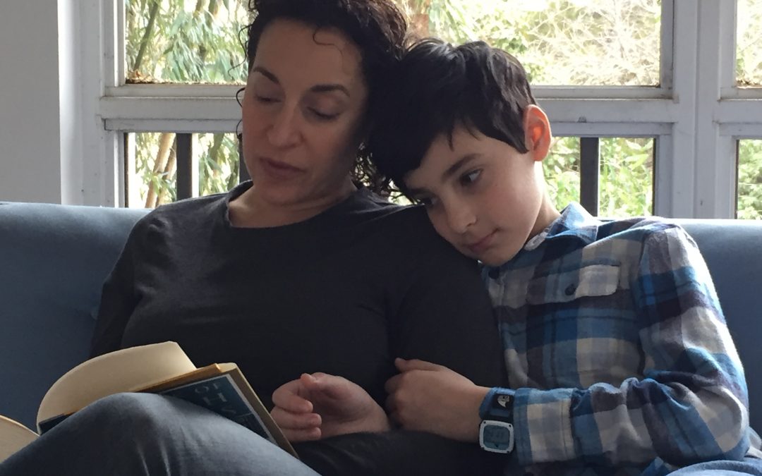 Woman reading aloud to her son on a couch