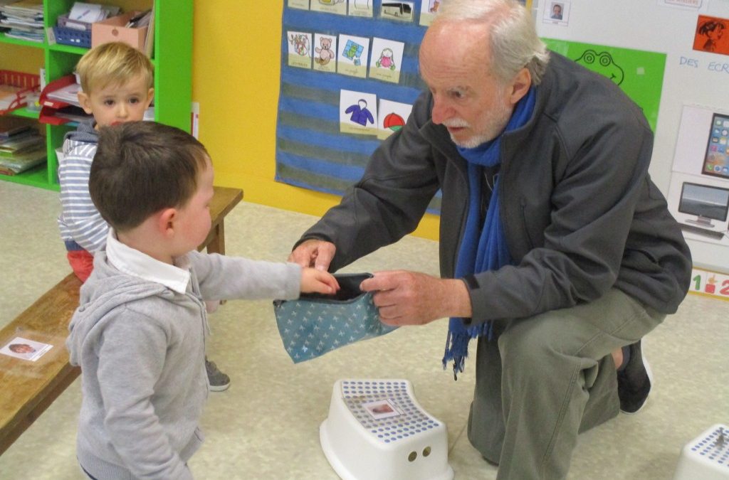 Jacques Brodeur crouching and speaking to child in classroom