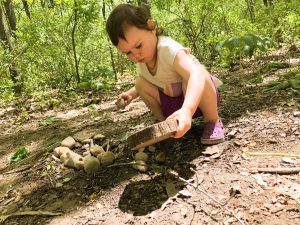 Child playing in the dirt with tree cookie