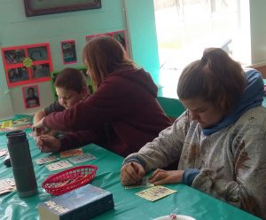 3 people working on an art project at table with green table cloth